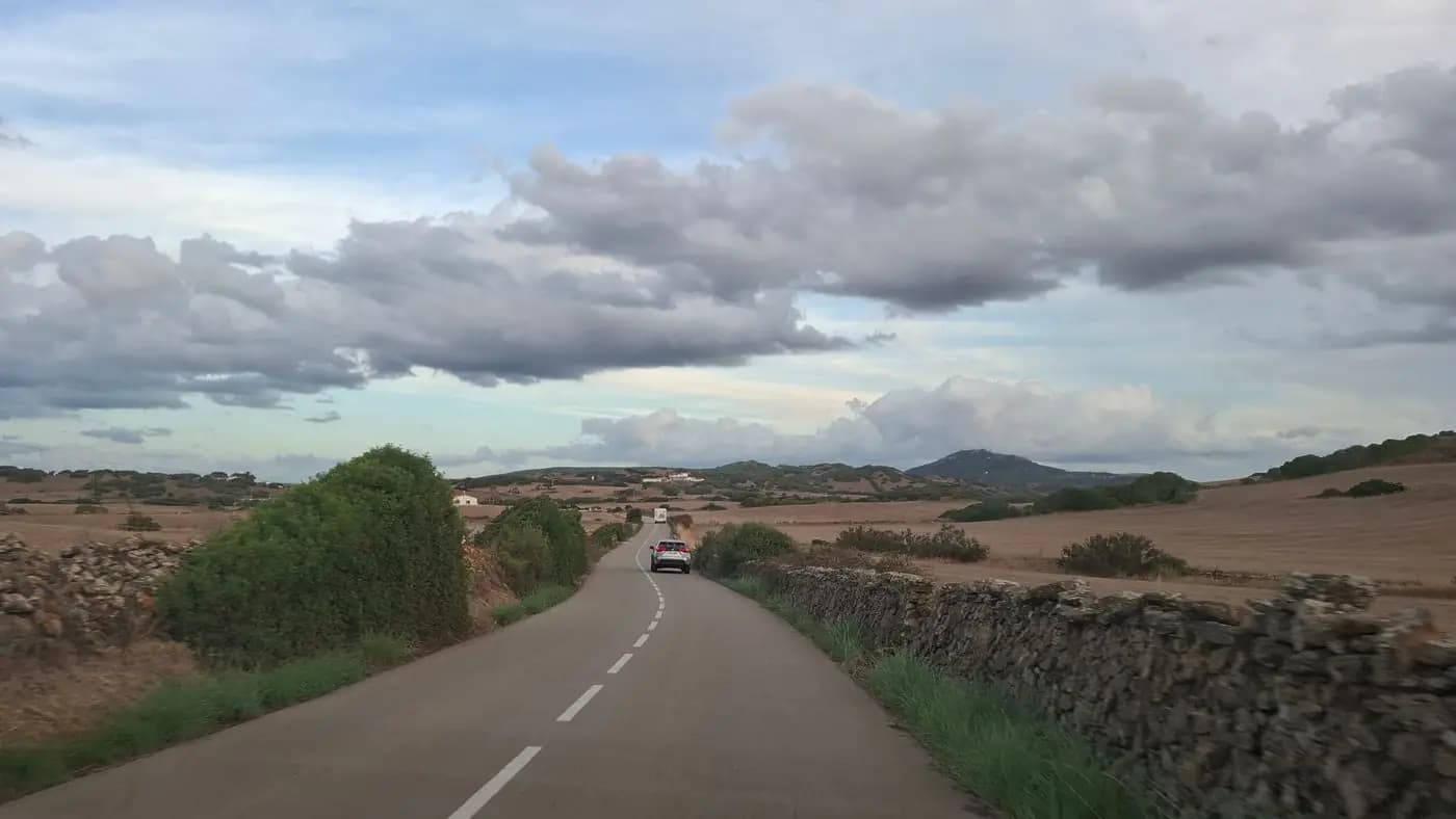 طريق ريفي تصطف على جانبيه جدران حجرية جافة في مشهد منورقة الطبيعي