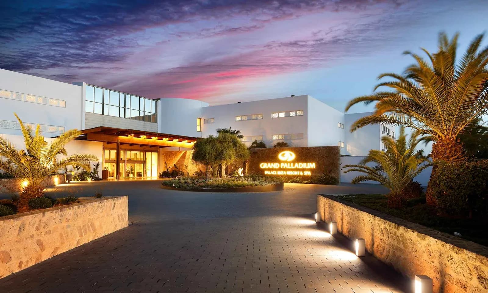 Entrance of Grand Palladium Palace Ibiza Resort & Spa at dusk with palm trees
