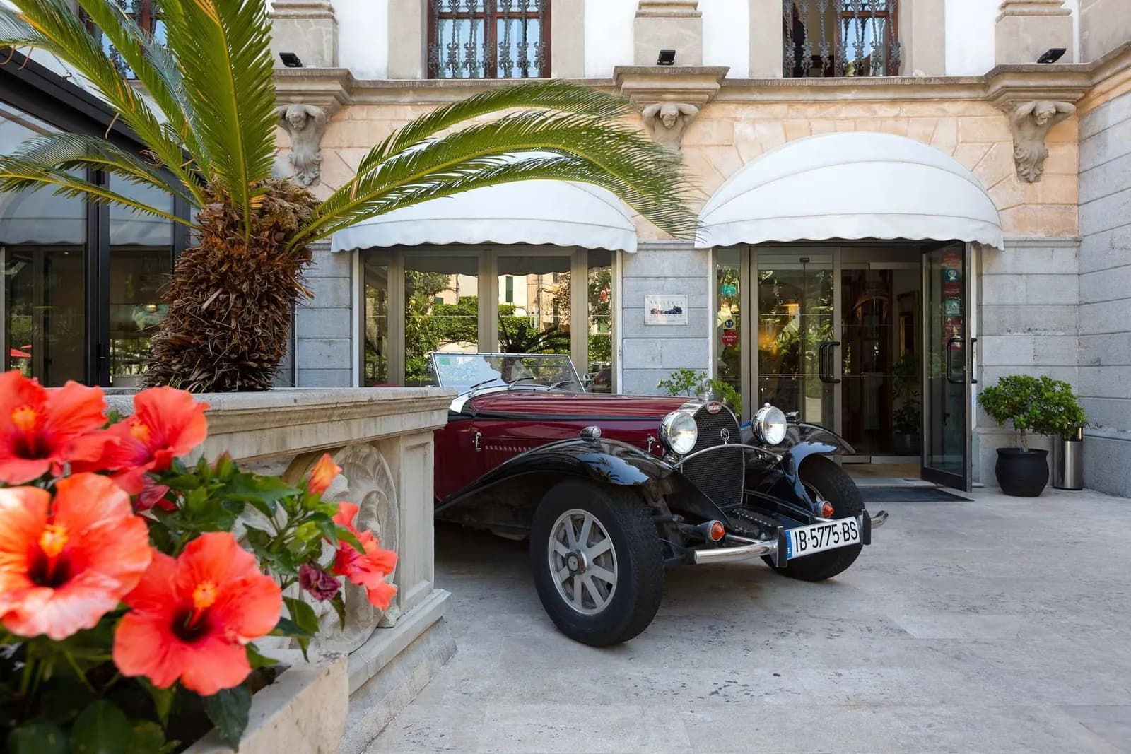 Entrance of Gran Hotel Sóller with a vintage car parked outside in Sóller