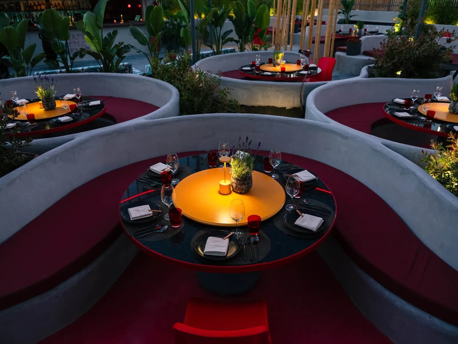Chi Kee Wun terrace in Ibiza with circular red booths and lit round tables at night