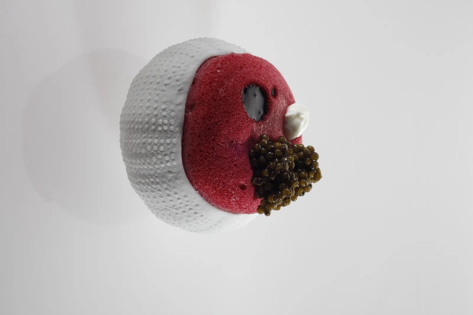 Gastronomic creation at Disfrutar restaurant in Barcelona, white and red sphere on pale background