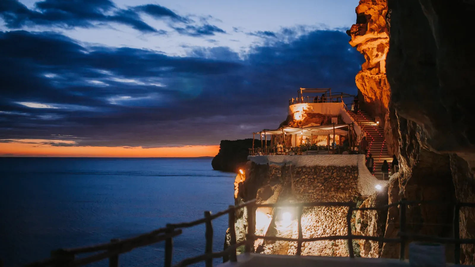 Cova d'en Xoroi lit up at night, bar carved into the rock in Menorca