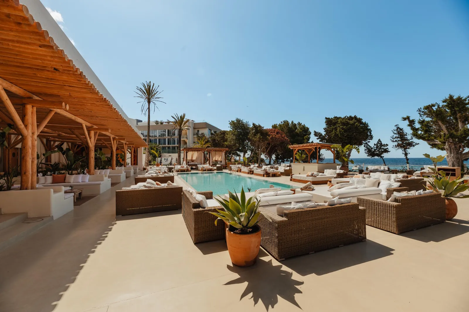 Pool and loungers at Nikki Beach Ibiza facing the sea, with palm trees