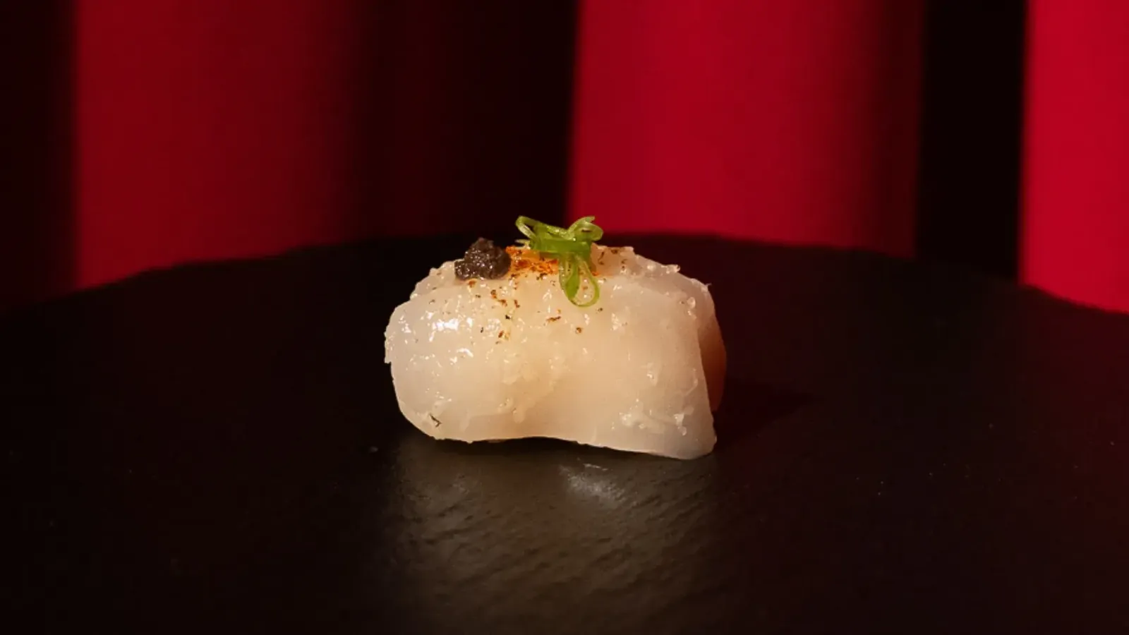 Raw hamachi piece on dark plate at Pacha Ibiza restaurant