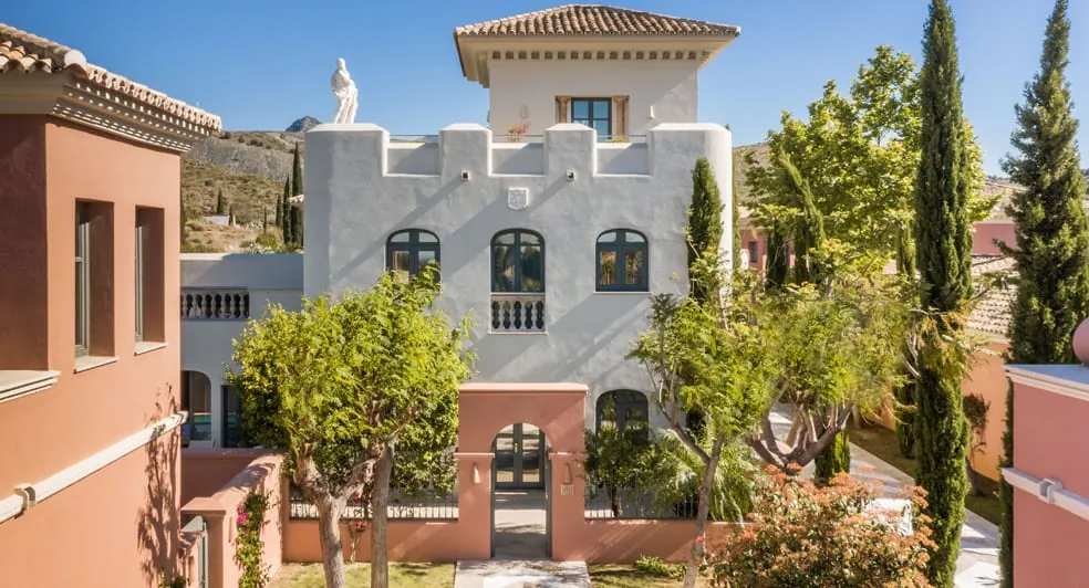 White and pink villa at Anantara Villa Padierna in Benahavís surrounded by cypress trees