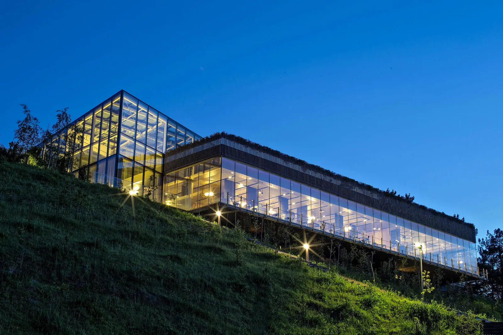 Façade vitrée de l'Azurmendi éclairée au crépuscule sur une colline à Larrabetzu