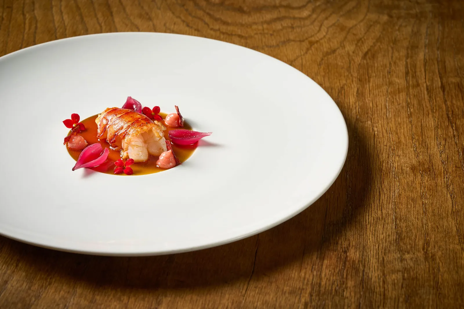 Assiette blanche garnie de crustacé rouge et de fleurs à Azurmendi