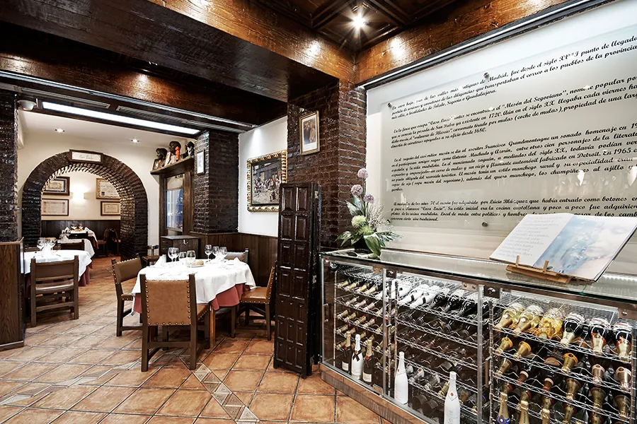 Dining room of Casa Lucio restaurant in Madrid with white-clothed tables and wine display