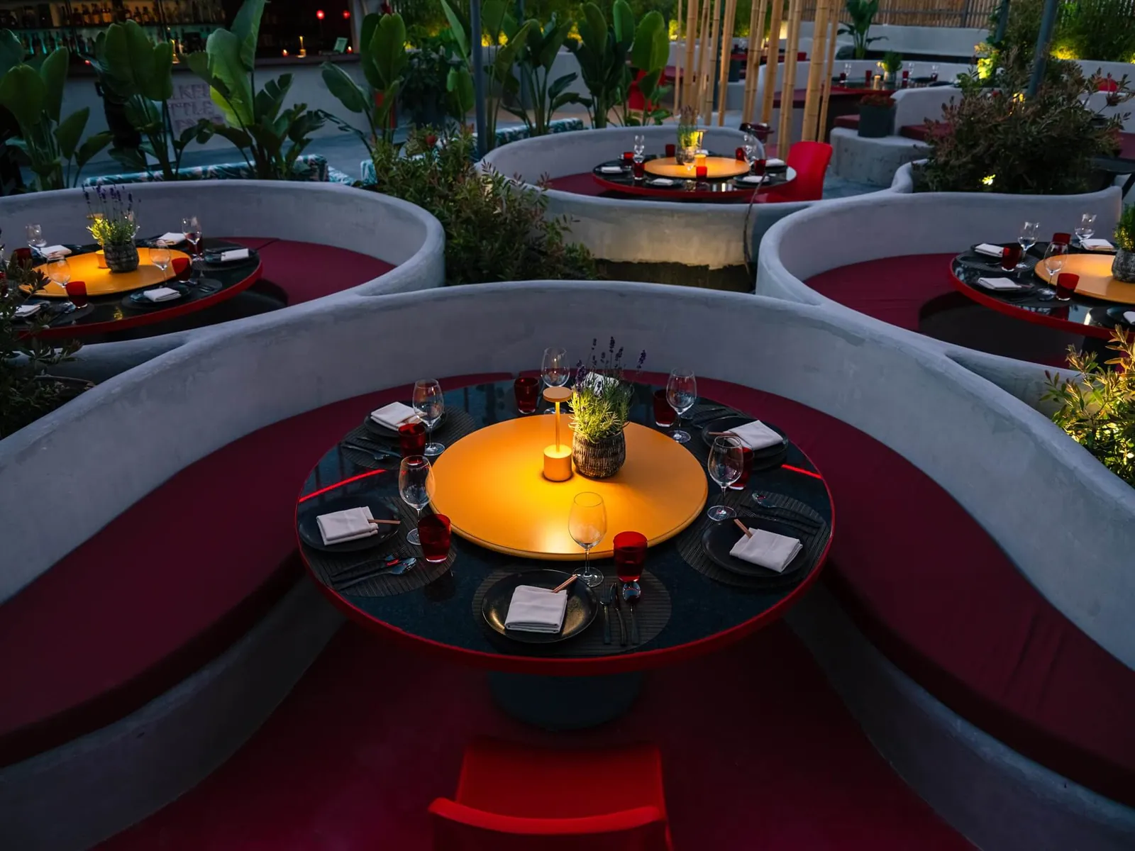 Chi Kee Wun terrace in Ibiza with circular red booths and lit round tables at night