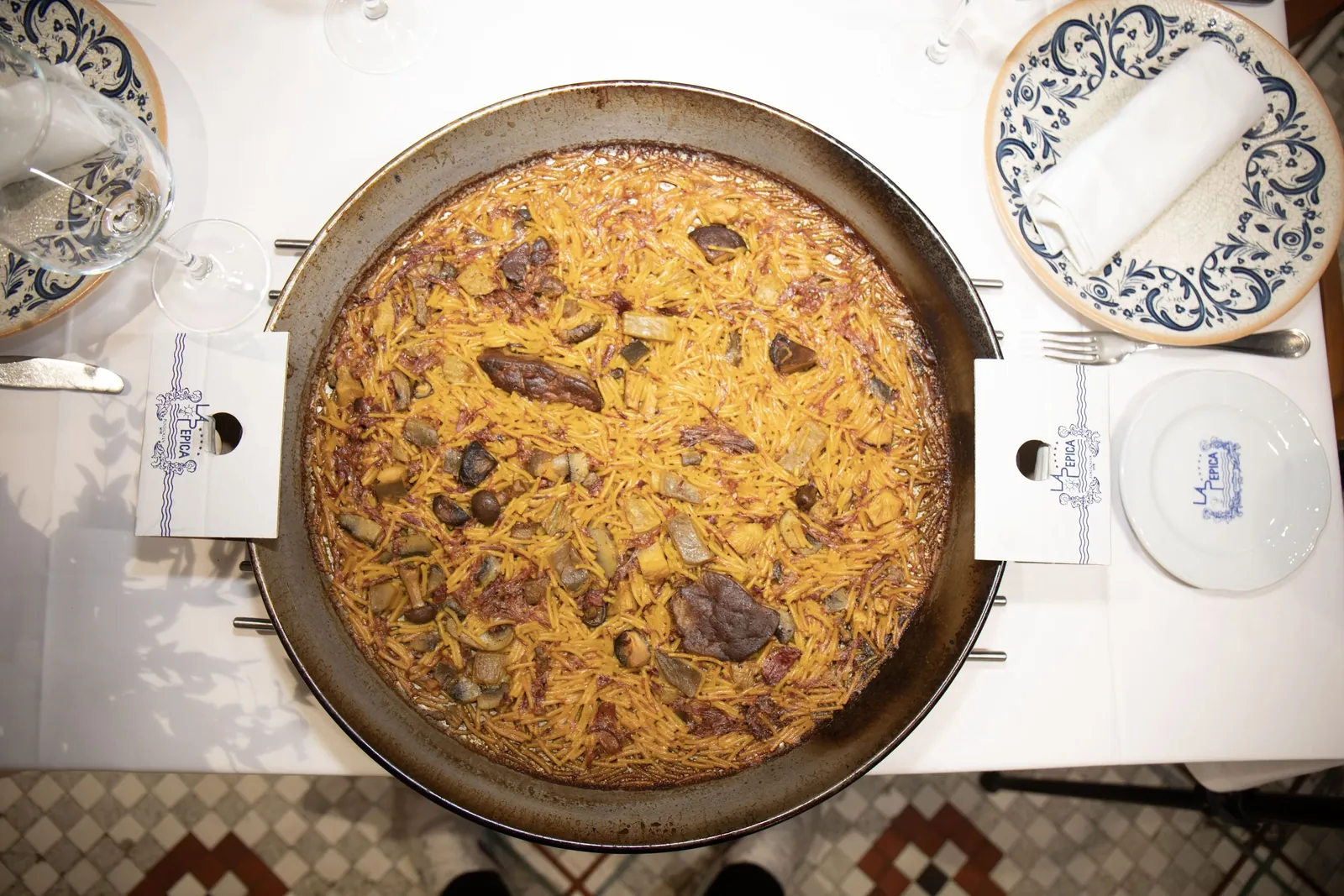 Top view of paella in the pan with blue plates at La Pepica, Valencia