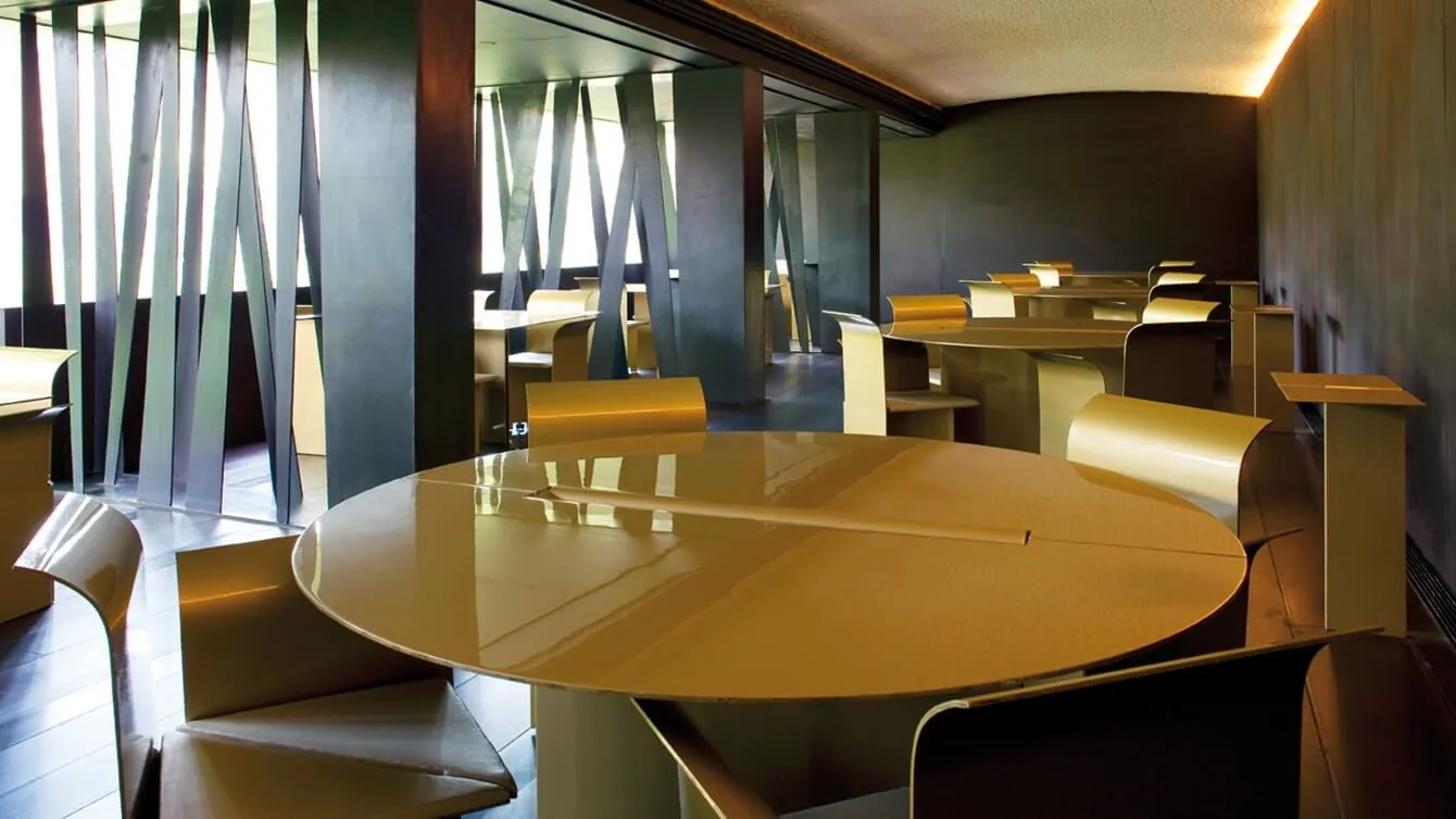 Dark wood-panelled dining room with round table at Les Cols, Olot