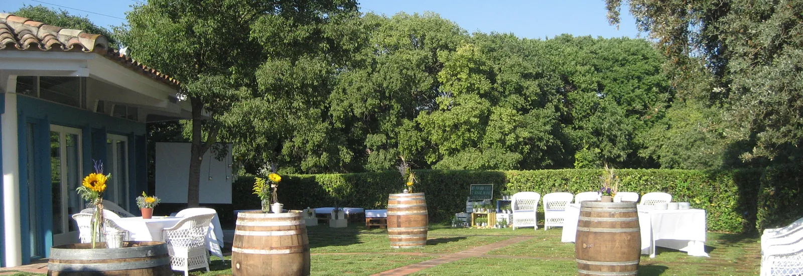 Outdoor area at Mas Rabell with white tables under trees and barrels