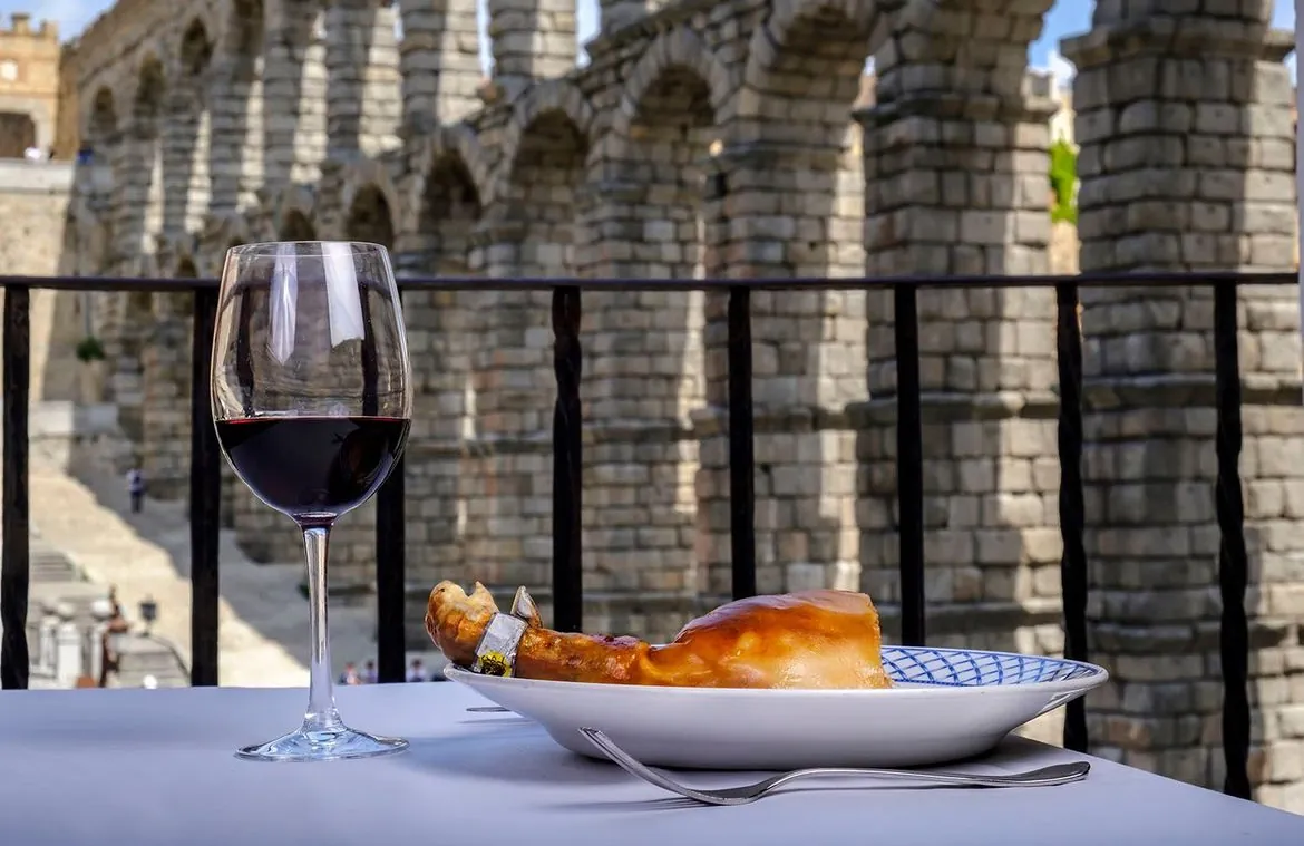 Roast suckling pig and red wine facing the Segovia aqueduct at Mesón de Cándido