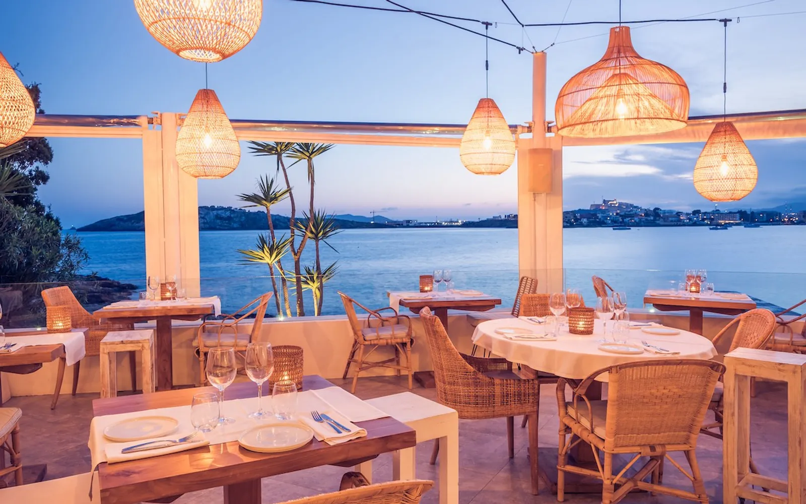 Sa Punta sea-view terrace with wicker lamps and set tables in Ibiza