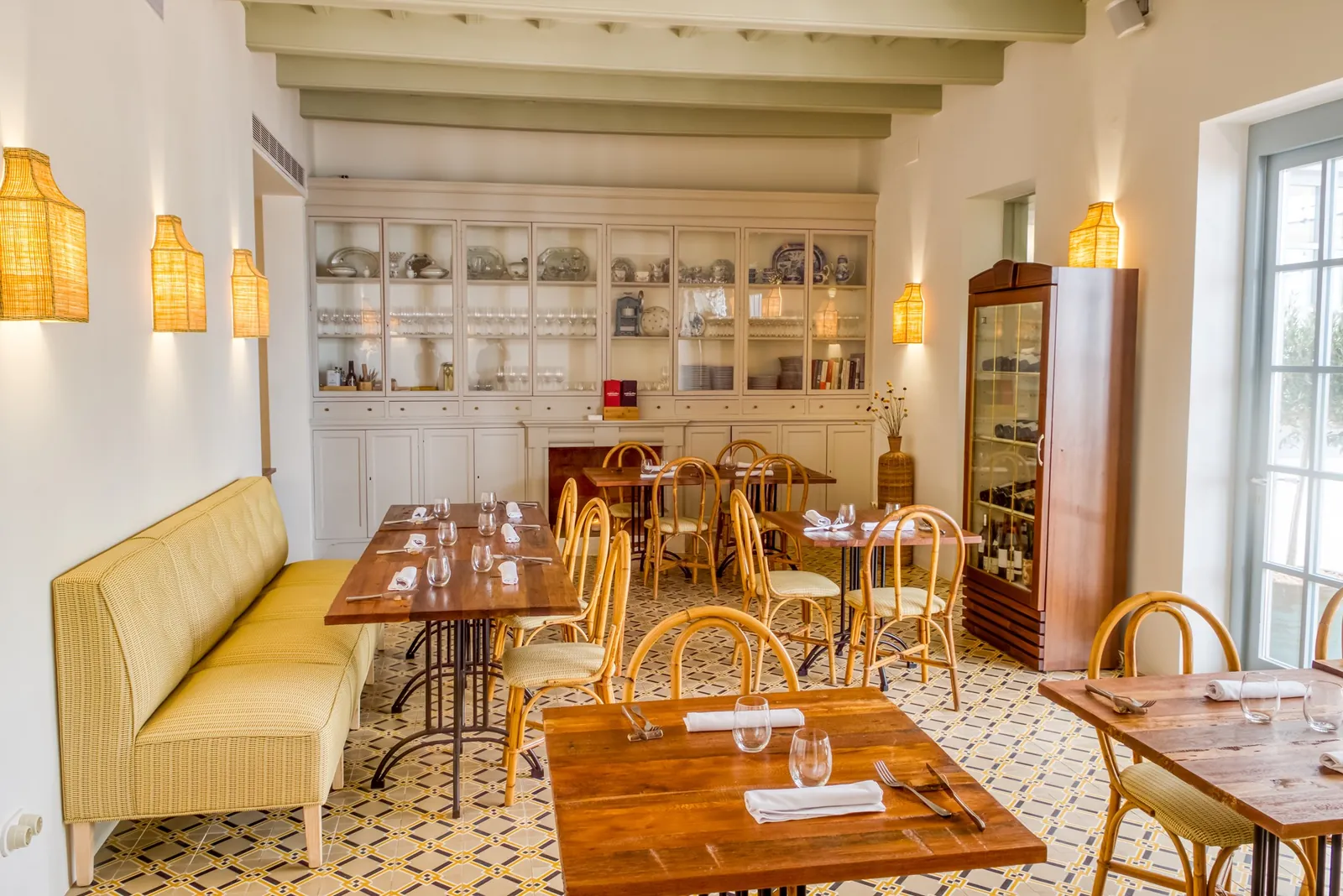 Bright room with yellow banquettes and wooden tables at Ses Forquilles in Mahón