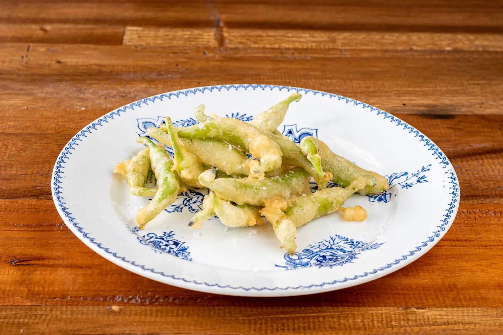 Fried green vegetables served on a blue-rimmed plate at Ses Forquilles in Mahón