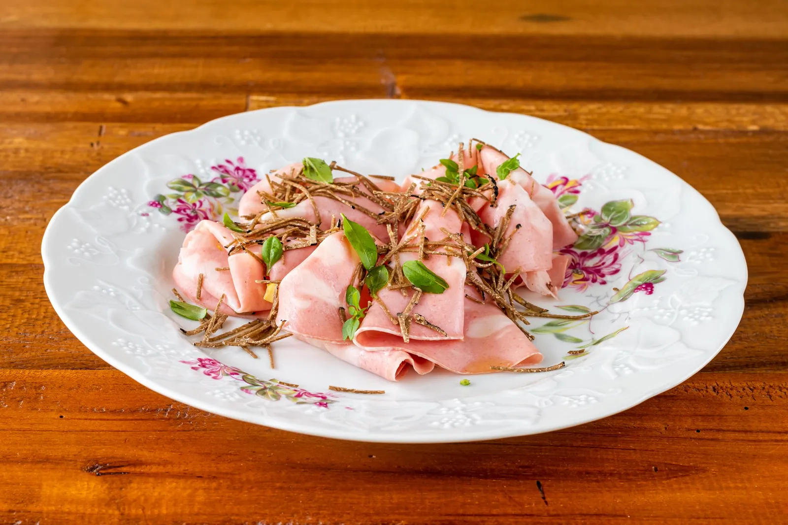 Thin slices of cured meat plated on porcelain at Ses Forquilles in Mahón