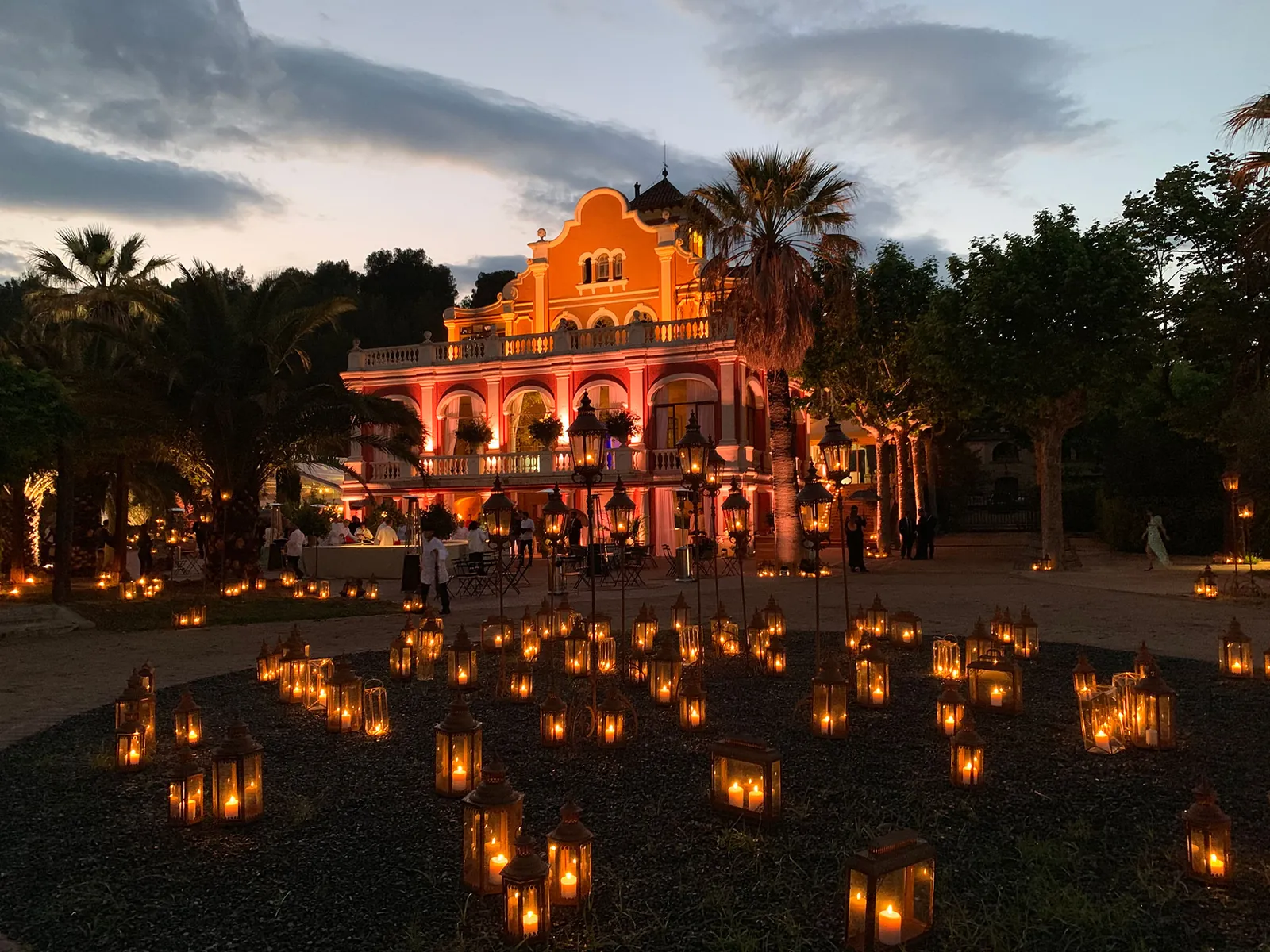 Evening at Castell de Ben Viure, lit façade and lanterns on the lawn