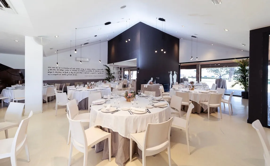 Large white hall with round tables and chandeliers at Espacio Villafranca in Madrid, set for dinner