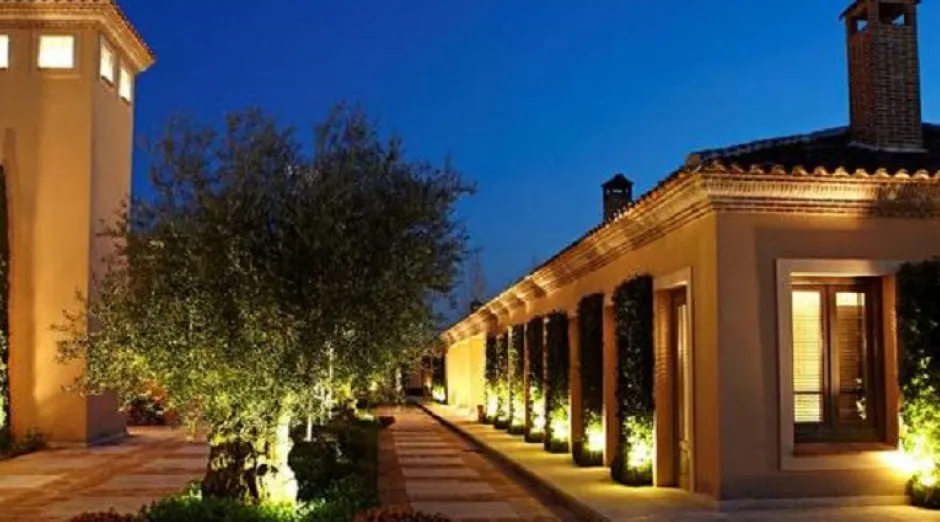Facade of La Quinta de Jarama at dusk, with arcade and olive trees, near Madrid