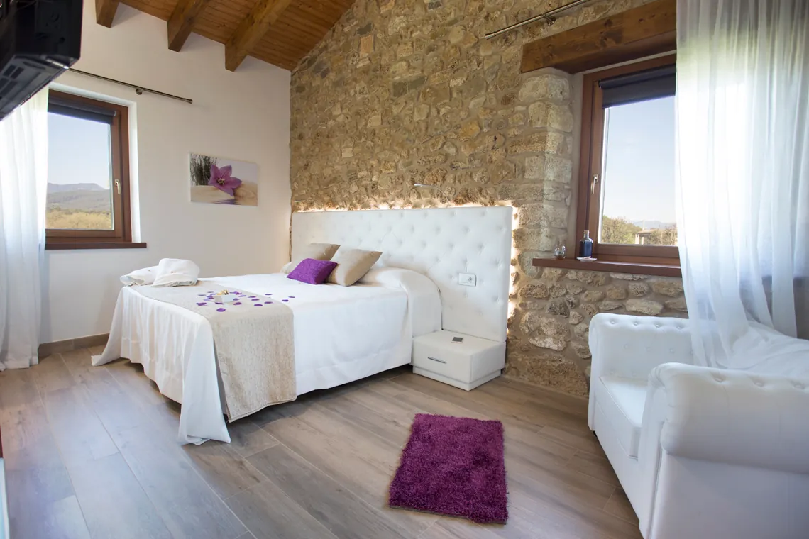 Bedroom with white bed and stone wall